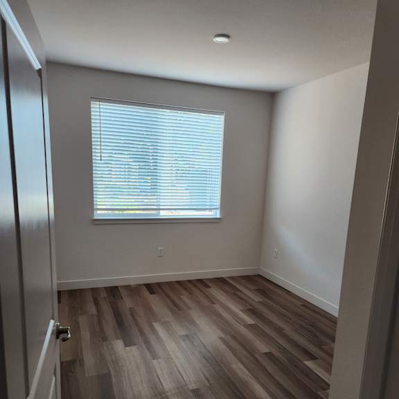 a room with a wooden floor and a window with blinds.