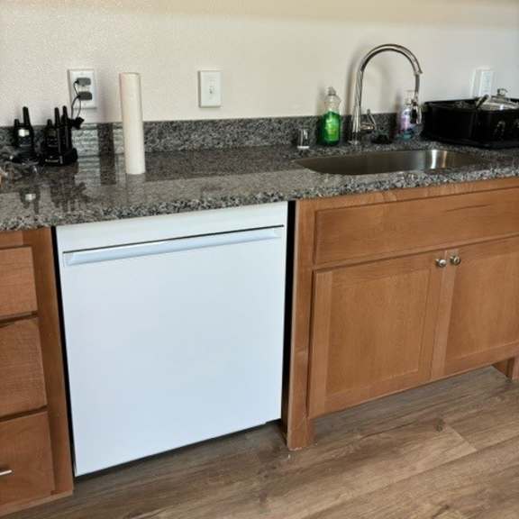 a kitchen with a white dishwasher and wooden cabinets.