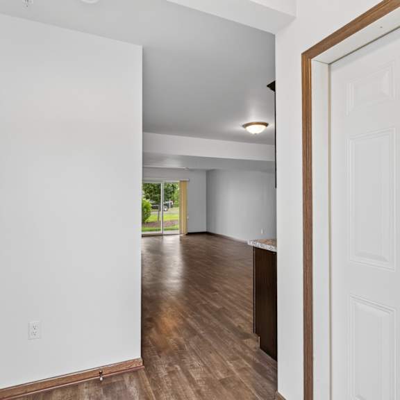 a white door is open to a room with wood floors.