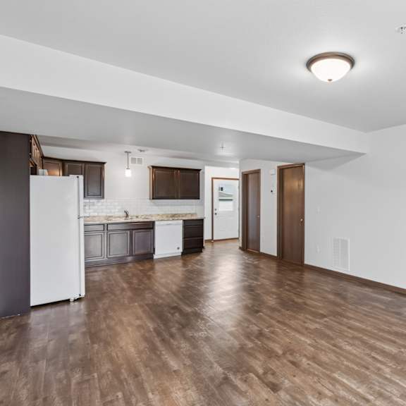 a kitchen with white appliances and wooden floors.