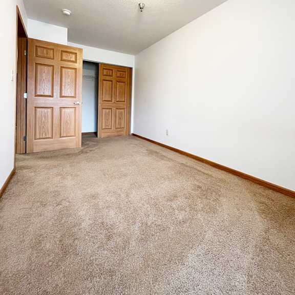 a room with a carpeted floor and two doors.