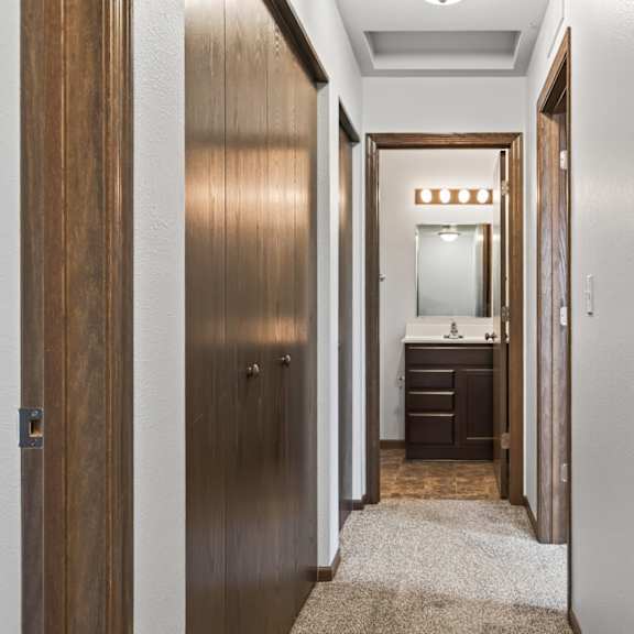 a hallway with a wooden door and a carpet on the floor.