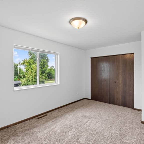 a room with a carpeted floor, a window, and a wooden door.