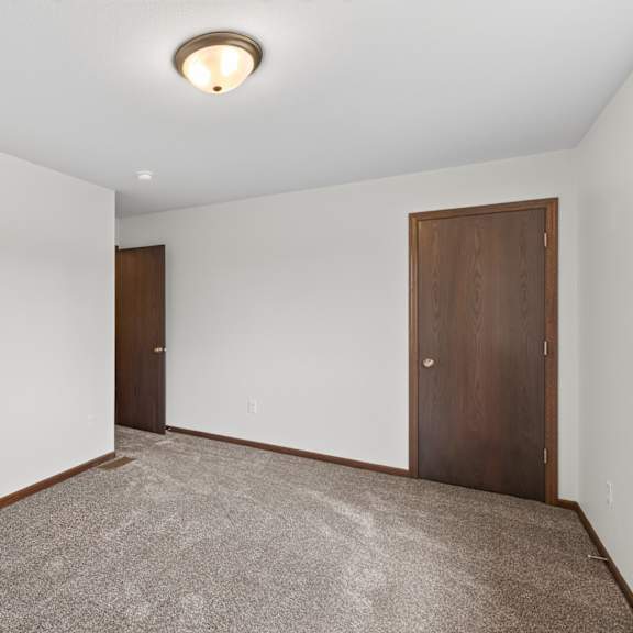 a room with two doors and carpeted floor.