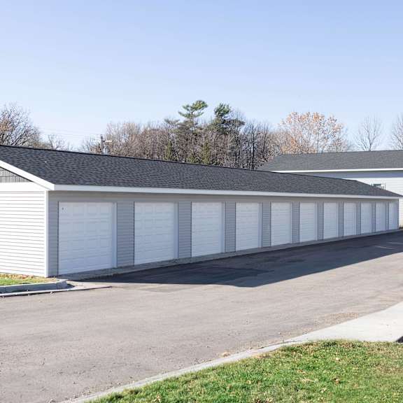 a long white garage with a black roof and a white car parked in front.