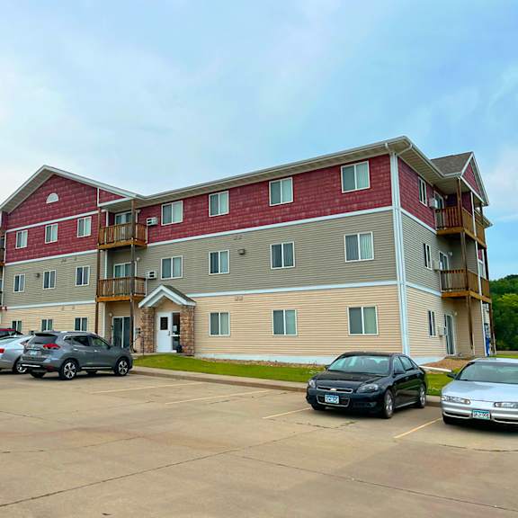 a parking lot in front of a multi-story apartment building.