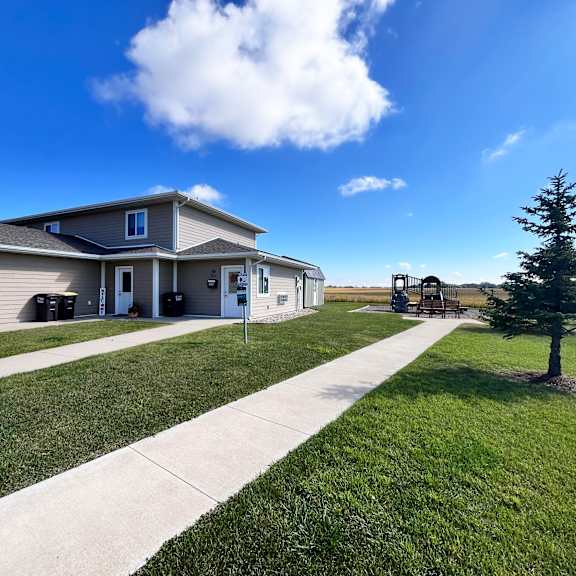 a house with a well-maintained lawn and a clear blue sky.