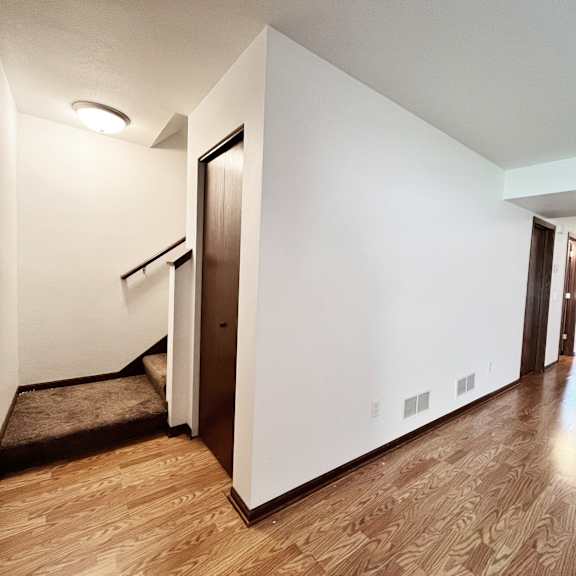 a hallway with a brown floor and white walls.