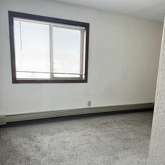 a room with a carpeted floor and a window with blinds.