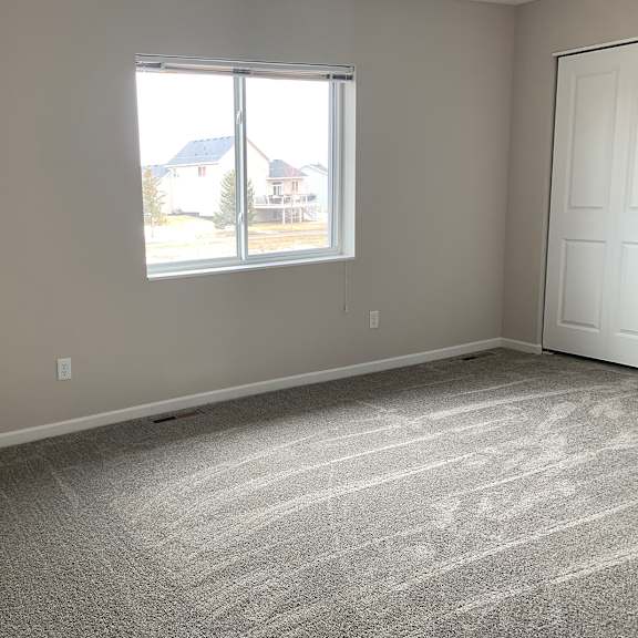 an empty bedroom with two doors and a window