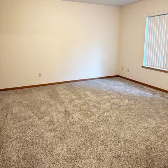 a room with a carpeted floor and a window with blinds.