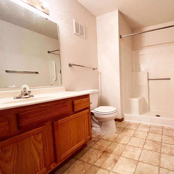 a bathroom with a toilet, sink, and shower.