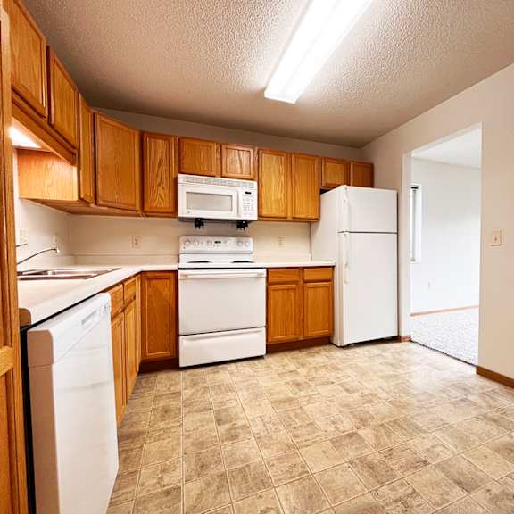 a kitchen with white appliances and wooden cabinets.