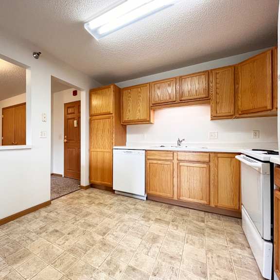 a kitchen with white appliances and wooden cabinets.