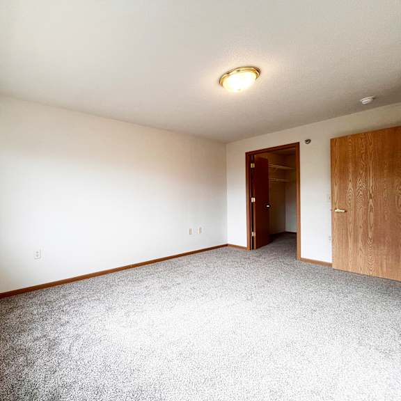 a room with a carpeted floor, a window, and a door.
