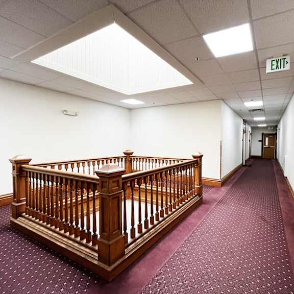 a hall with a wooden staircase and a exit sign
