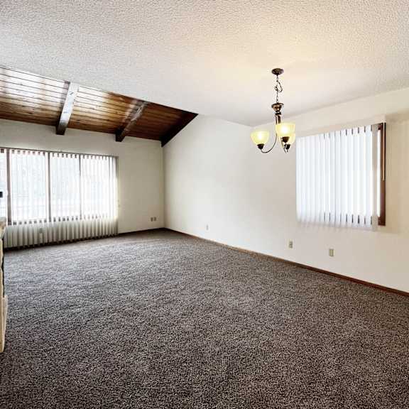 a room with a carpeted floor and a chandelier hanging from the ceiling.