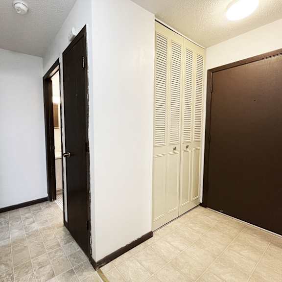 an empty hallway with two doors and a closet