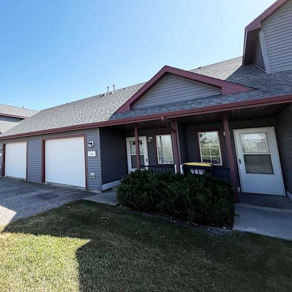 a house with two garage doors and a sidewalk in front of it