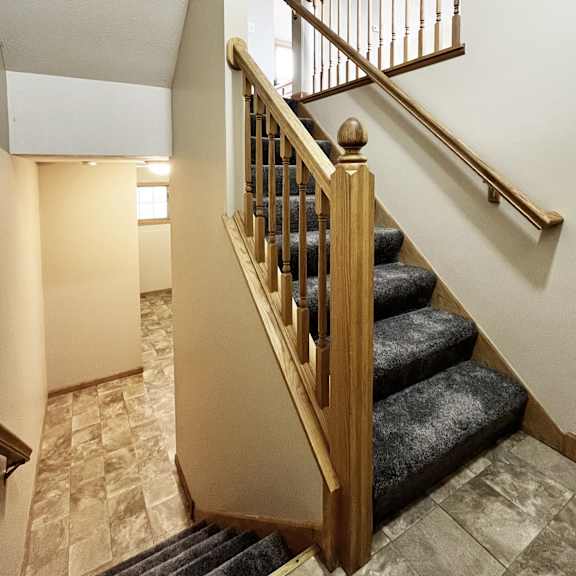 a staircase with a wooden banister and a carpeted stair runner.