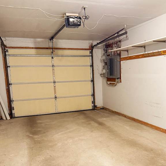 a garage with a closed white door and a wall-mounted tv.