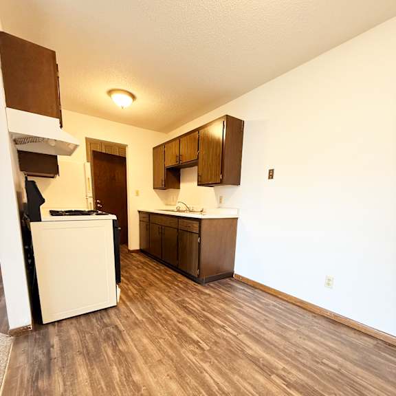 a kitchen with white appliances and wooden floors.