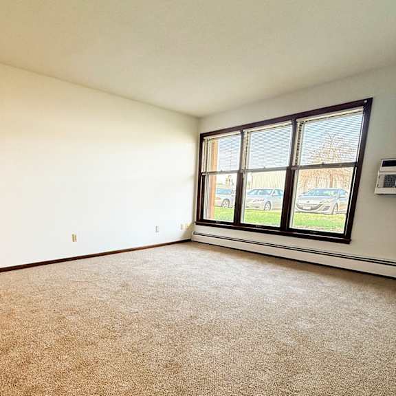 a room with a carpeted floor and a window showing a parking lot outside.