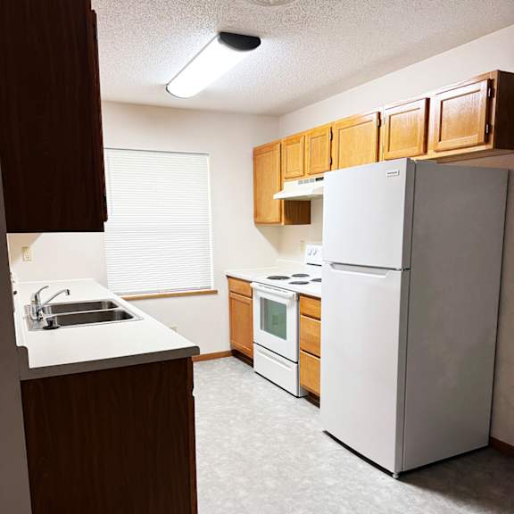 a kitchen with a white refrigerator, sink, and stove.