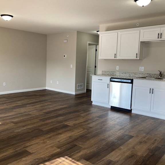 a kitchen and living room with hardwood floors and white cabinets