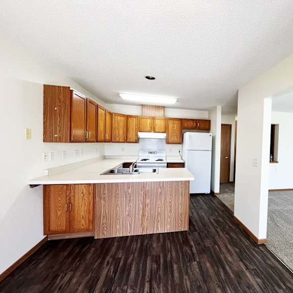 an empty kitchen with wooden cabinets and a white refrigerator