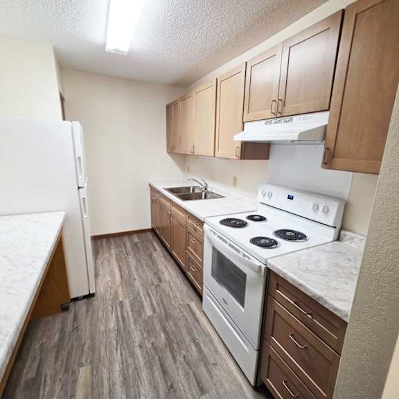 a kitchen with a white fridge, white stove, and brown cabinets.