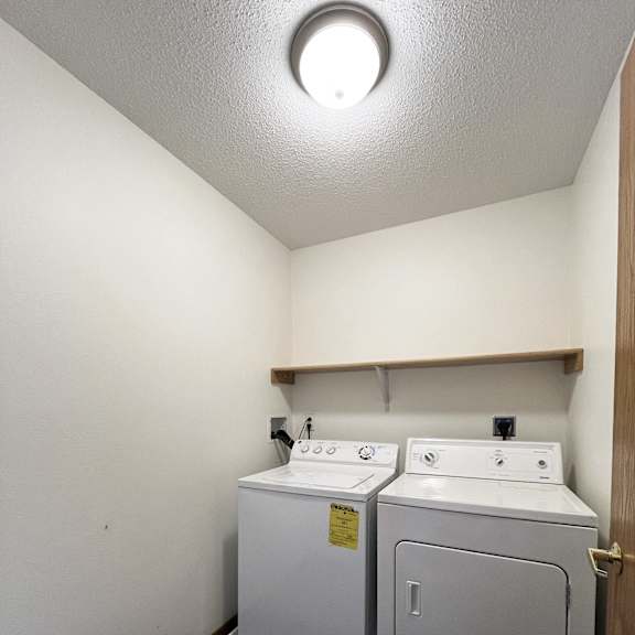 a room with two washers and a dryer in it and a white wall