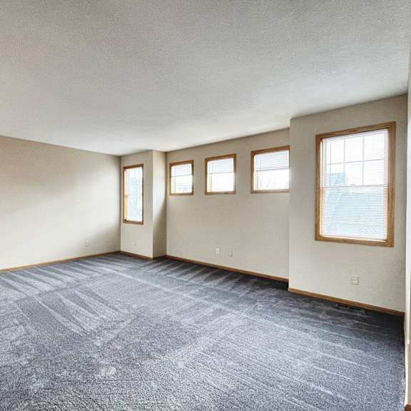 a room with a carpeted floor and three windows.