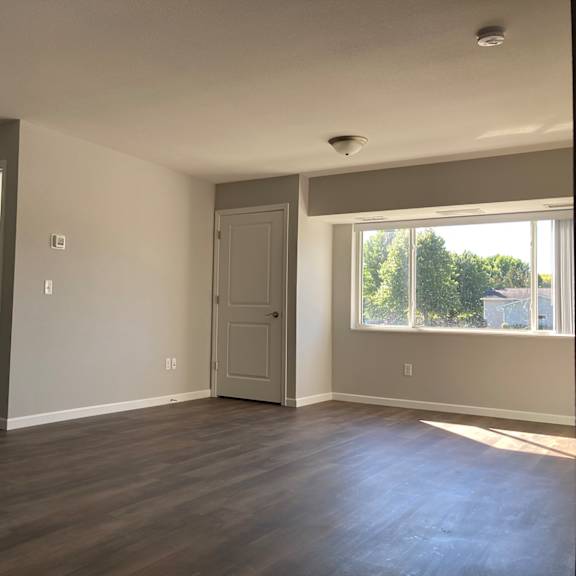a room with a white door and a window with trees visible outside.
