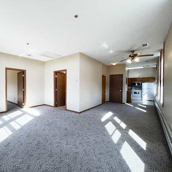 an empty living room with white walls and a ceiling fan