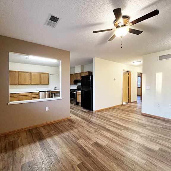 a room with a ceiling fan and wooden flooring.