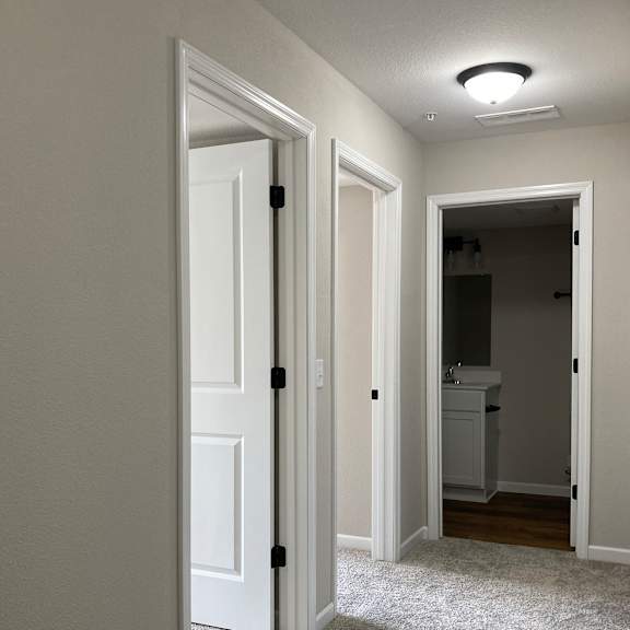 a doorway into a bedroom with a carpeted floor and a bathroom in the background