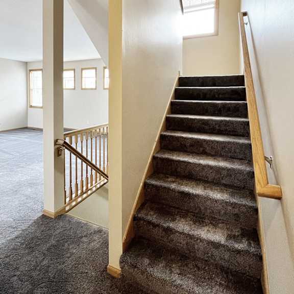 a staircase with a carpeted runner and wooden handrail.