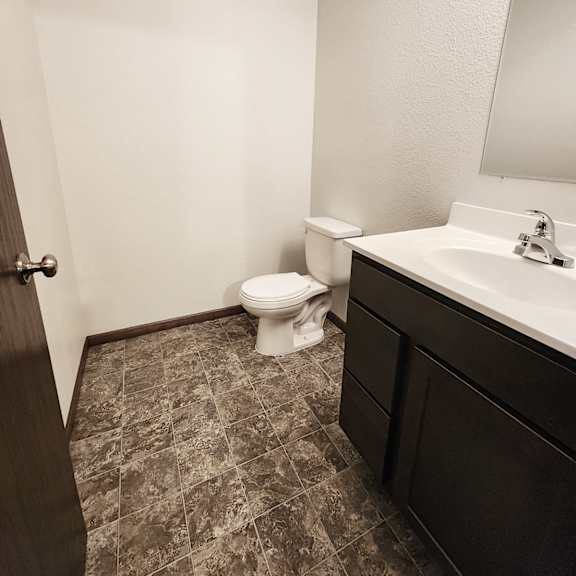 a bathroom with a toilet, sink, and mirror.