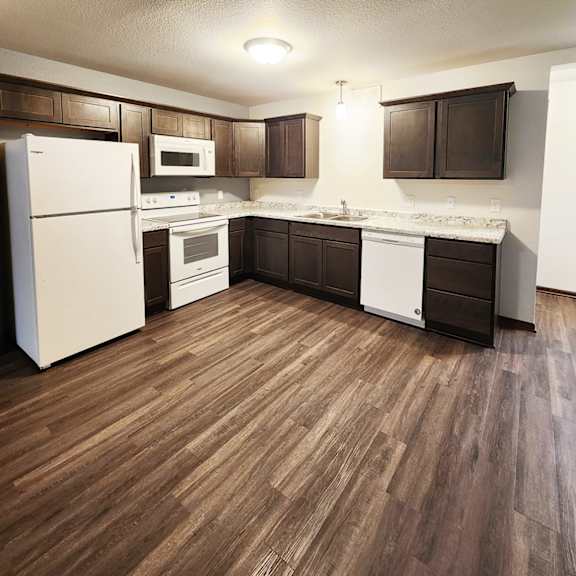 a kitchen with white appliances and brown cabinets.