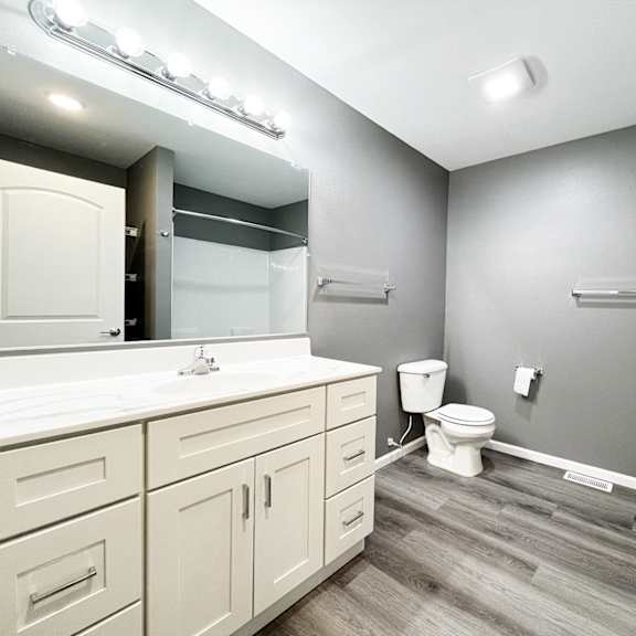 a bathroom with a white counter top and a white toilet.