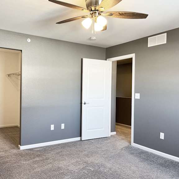a room with a ceiling fan and carpeted floor.