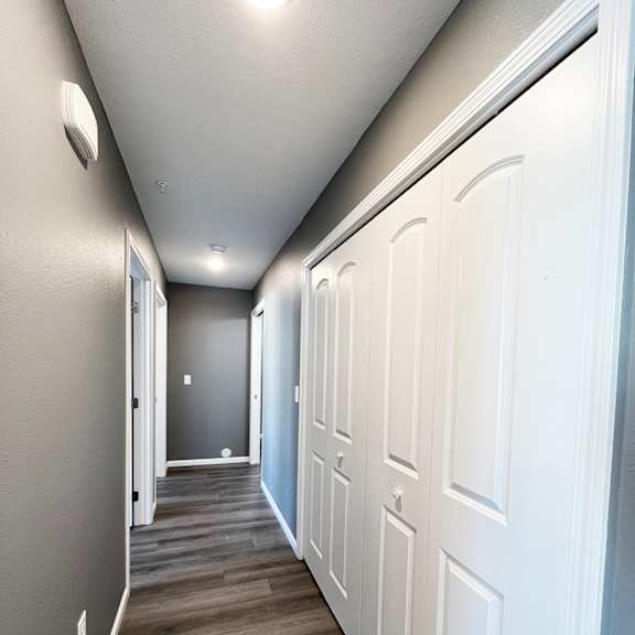 a long hallway with white doors on the right and a grey wall on the left.