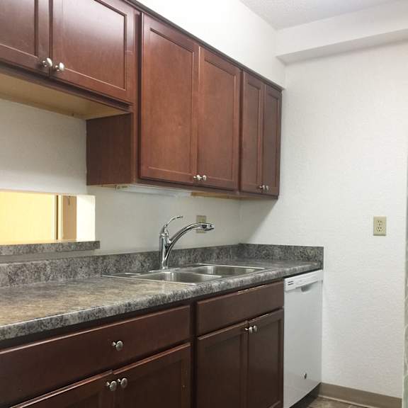 a kitchen with brown cabinets and a granite countertop.
