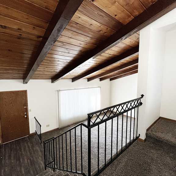 a room with a wooden ceiling and a black railing.