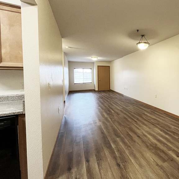 a long, empty hallway with wooden floors and white walls.