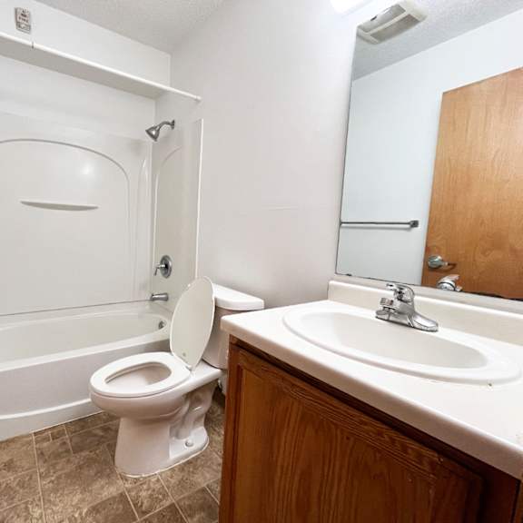 a white toilet is in a bathroom with a white tub and sink.