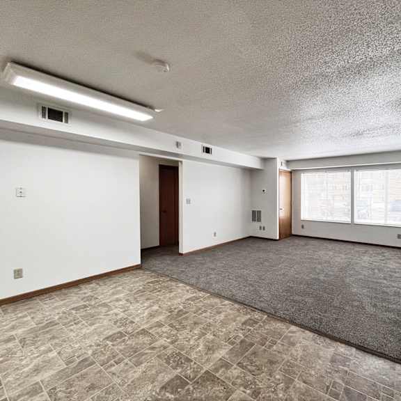 a spacious room with a carpeted floor and large windows.