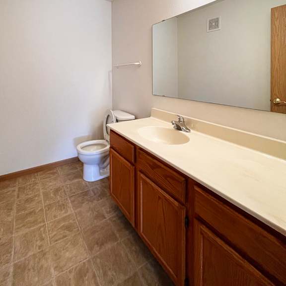 a bathroom with a toilet, sink, and mirror.