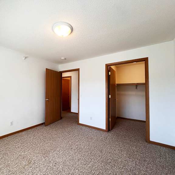 a carpeted room with two doors and a ceiling light.